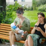 two women sitting on a bench with a baby
