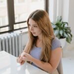 Woman with long hair sitting and using sign language at a table indoors.