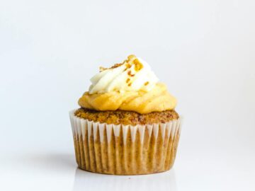 A delectable cupcake with creamy frosting on a white background, perfect for food photography.