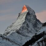 Stunning view of the snowcapped Matterhorn at sunrise, illuminating the peak in a warm glow, Zermatt, Switzerland.