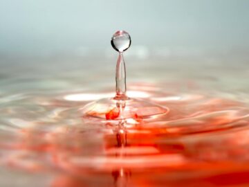 Macro capture of a droplet splash on a surface with a reflection and colored water effect, creating an artistic view.
