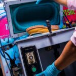 Worker using industrial equipment with safety gloves for precision manufacturing process.