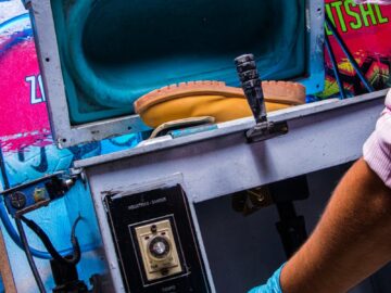 Worker using industrial equipment with safety gloves for precision manufacturing process.