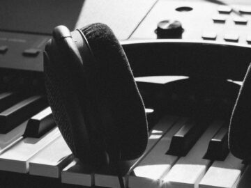 Close-up of headphones resting on piano keys, capturing the essence of music creation.