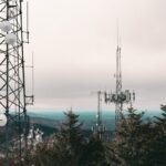 Vertical shot featuring cell towers surrounded by a snow-covered forest landscape.