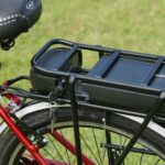 Detailed view of an electric bicycle battery mounted on a rear rack, highlighting the key-lock mechanism.