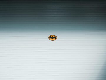 A minimalist Batman logo on a metallic roll-up door in daylight, Shilin District, Taipei.