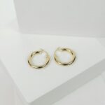 Chic gold hoop earrings displayed on a minimalist white surface, perfect for fashion collections.