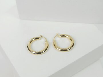 Chic gold hoop earrings displayed on a minimalist white surface, perfect for fashion collections.