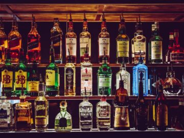 An array of various liquor bottles beautifully displayed on a bar shelf.