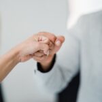 Close-up of two professionals bumping fists, symbolizing teamwork and respect in a modern office.