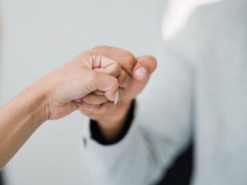 Close-up of two professionals bumping fists, symbolizing teamwork and respect in a modern office.