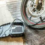 Close-up of a motorcycle tire being inflated using a portable air pump.