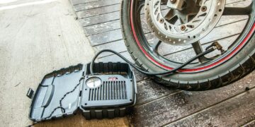Close-up of a motorcycle tire being inflated using a portable air pump.