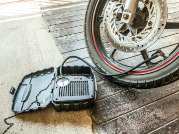 Close-up of a motorcycle tire being inflated using a portable air pump.