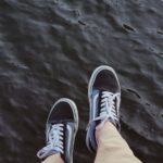 Casual black sneakers dangling above water, capturing a relaxed moment by the sea in İstanbul.