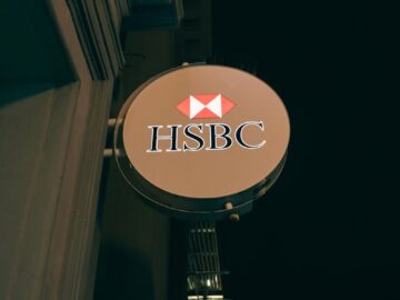 Vertical shot of an HSBC bank sign lit up at night, showcasing urban bank architecture.