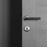 Close-up of a modern gray door with a sleek metal handle and keyhole.