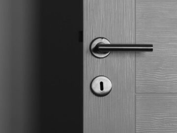 Close-up of a modern gray door with a sleek metal handle and keyhole.