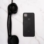 Comparison of a vintage handset with a modern smartphone on a marble surface.