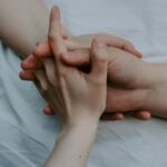 Intimate close-up of hands interlocked on a soft surface, symbolizing connection and love.