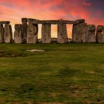 Capture of the iconic Stonehenge during a vibrant sunset with a dramatic sky.
