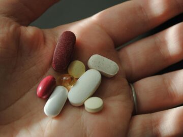 A close-up image of assorted pills and vitamins being held in a hand.