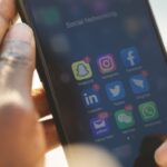 Close-up of a smartphone showing various social media applications being used.