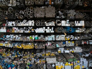 Diverse collection of stacked metallic pipes and rods in a warehouse display.
