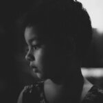A candid black and white portrait of a thoughtful child in side view.