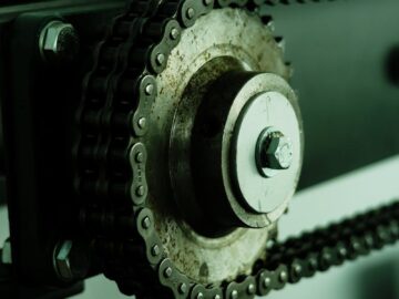 Detailed view of a rusty chain mechanism with a metal wheel, showcasing industrial engineering.