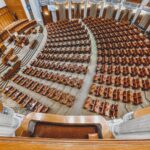 A grand European parliamentary chamber empty of people, showcasing rows of wooden seats.