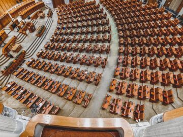 A grand European parliamentary chamber empty of people, showcasing rows of wooden seats.