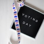 Close-up of a Voting Day sign and roll of I Voted stickers.