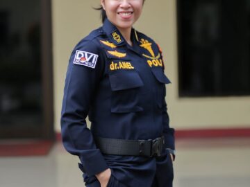 Asian female police officer smiling confidently while standing outdoors in Jakarta.