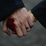 Intimate close-up of a couple holding hands, featuring henna tattoos and rings, taken in Malaysia.