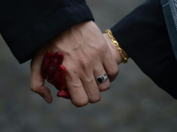 Intimate close-up of a couple holding hands, featuring henna tattoos and rings, taken in Malaysia.