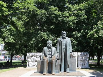 Statues of Karl Marx and Friedrich Engels in Berlin park, sunny day.
