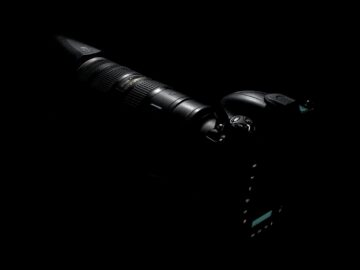 A sleek DSLR camera and lens highlighted against a dark background.