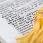 Close-up image of a dictionary page focused on the word 'dictionary' with a yellow tassel.