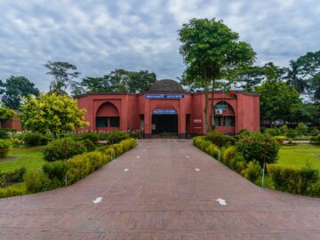 Scenic view of Bagerhat Museum entrance surrounded by lush greenery, showcasing historical architecture.