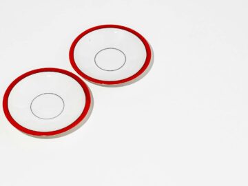 Top view of two white plates with red rims on a white background.