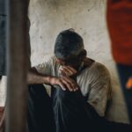 A senior adult man sits distraught indoors, conveying emotion and social issues.