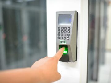 A person uses a fingerprint scanner for secure entry in a business setting.
