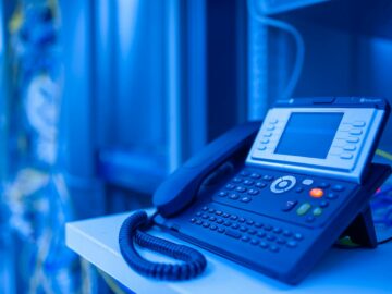 Close-up of a modern office phone in blue lighting. Ideal for tech and business themes.
