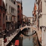 Serene Venetian canal scene featuring a gondola, historic buildings, and a picturesque bridge in Venice, Italy.