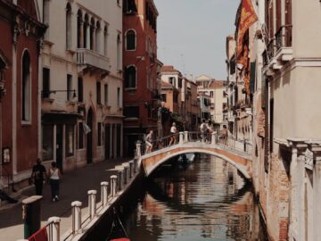 Serene Venetian canal scene featuring a gondola, historic buildings, and a picturesque bridge in Venice, Italy.