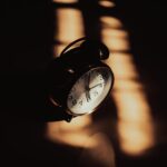 A retro analog alarm clock in moody shadows and warm lighting.