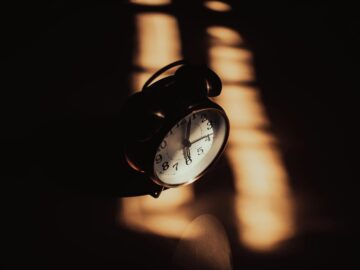 A retro analog alarm clock in moody shadows and warm lighting.
