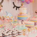 A vibrant unicorn-themed birthday party setup with cakes, cupcakes, and decorations.